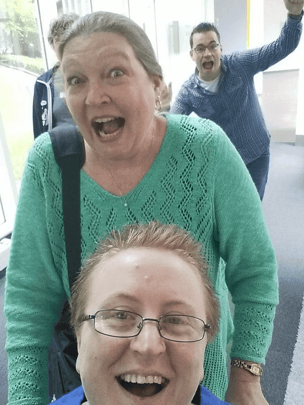 A photo of Ruth, seated in a wheelchair, and three friends behind her having fun, smiling and laughing.