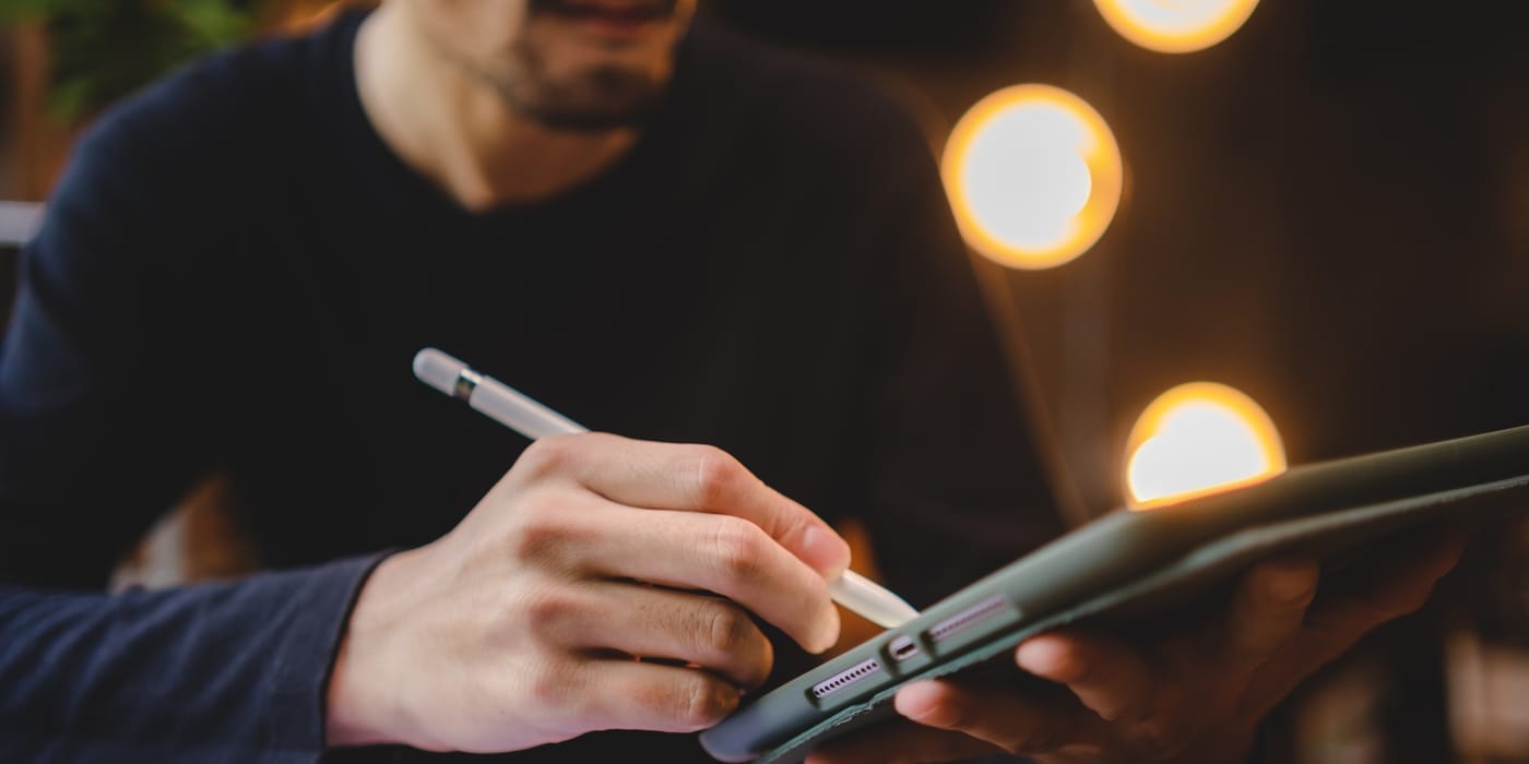 Photo of a man writing on a tablet with a stylus