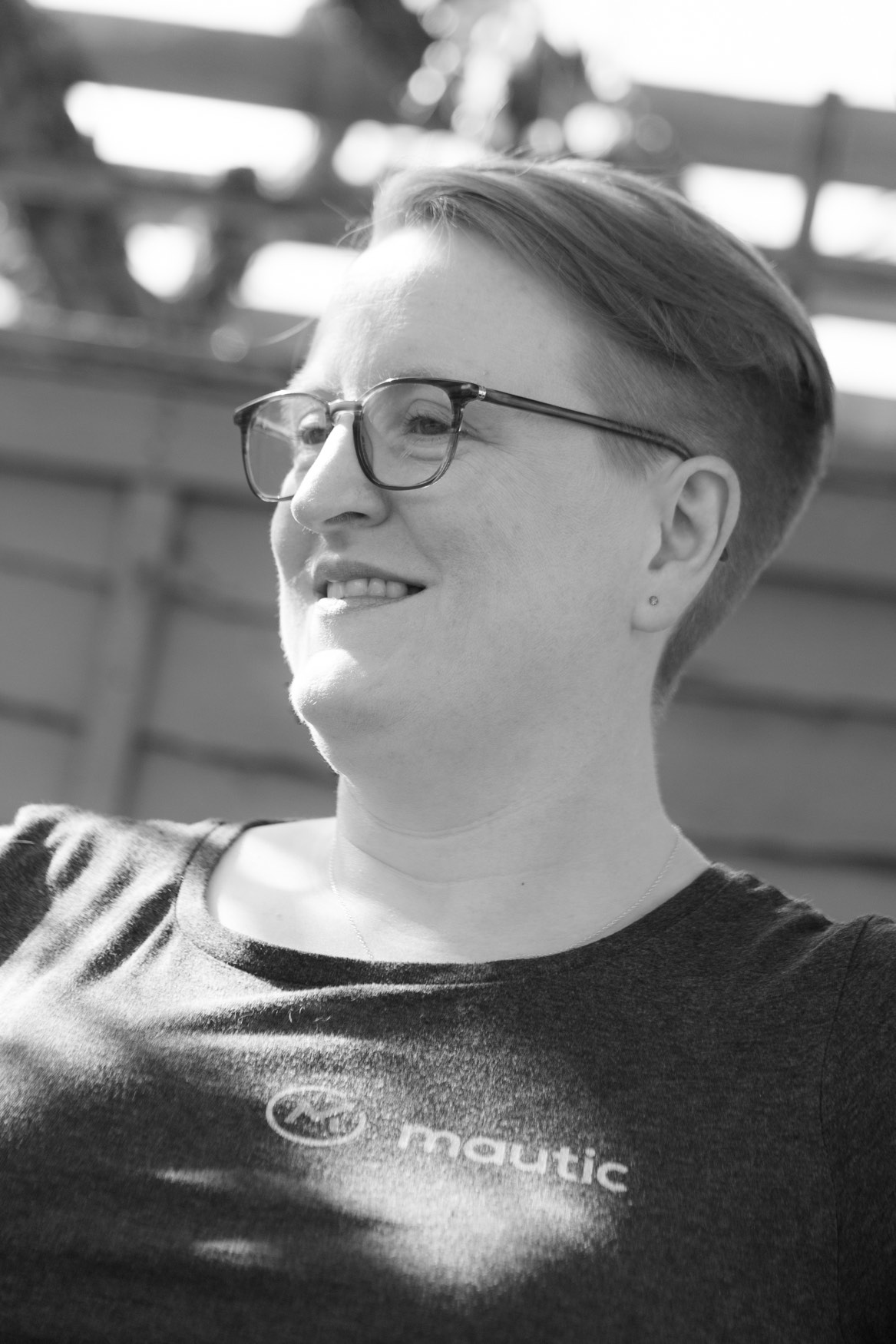 Black and white photo of Sīlavāpi outdoors in a Mautic T-shirt, looking to one side.