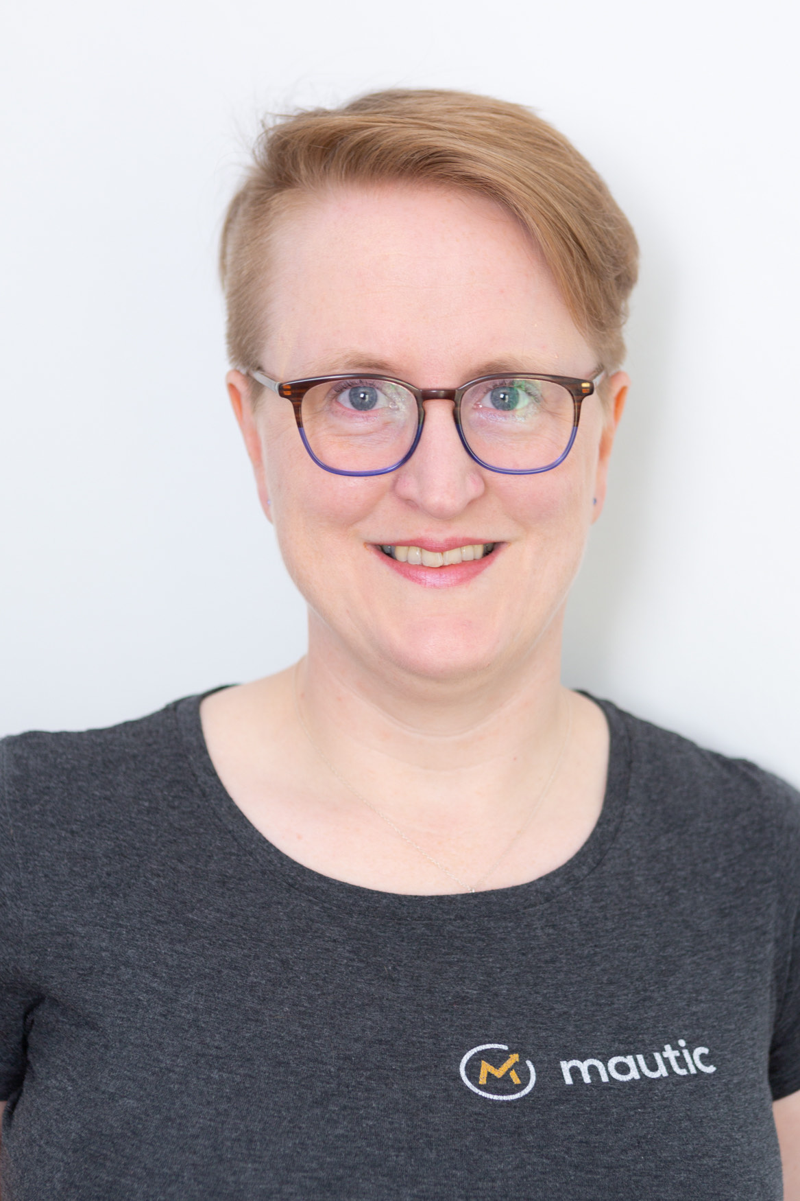 Sīlavāpi smiling to camera in a Mautic T-shirt against a plain pale background.