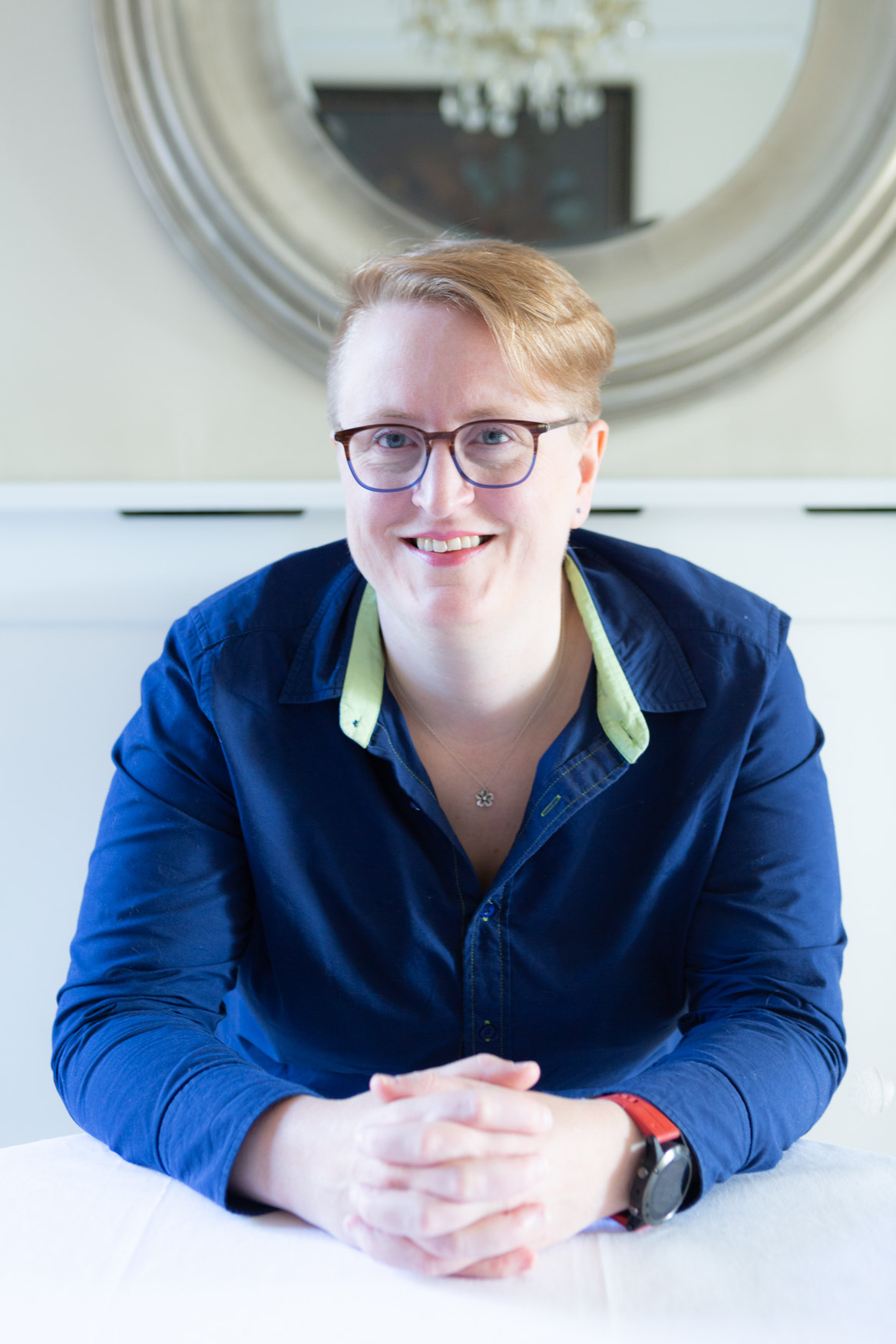 Sīlavāpi seated at a table with her hands folded, smiling to camera, wearing a navy shirt.
